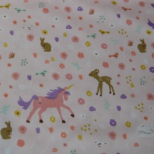 Op de afbeelding: Roze stof met een herhalend patroon van witte konijnen, bruine herten, gele vogels, paarse bloemen en roze eenhoorns.