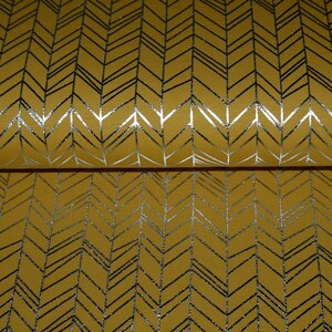 Könnte beinhalten: Ein gelber Stoff mit einem silbernen Chevron-Muster. Der Stoff hat einen dezenten Glanz und eine strukturierte Oberfläche.