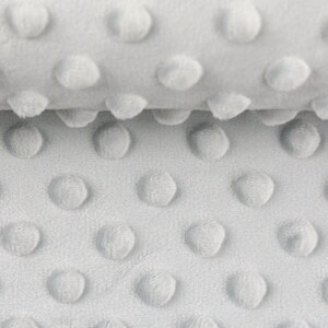 Könnte beinhalten: Nahaufnahme eines grauen, strukturierten Stoffes mit einem sich wiederholenden Muster aus kleinen, erhabenen Kreisen.