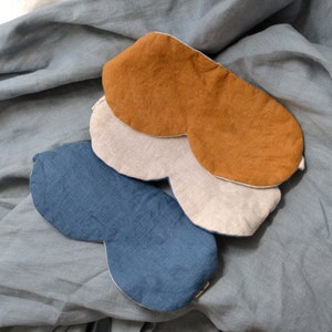 May include: Three sleep masks made of different fabrics. The top mask is a brown linen, the middle mask is a beige linen, and the bottom mask is a blue linen.