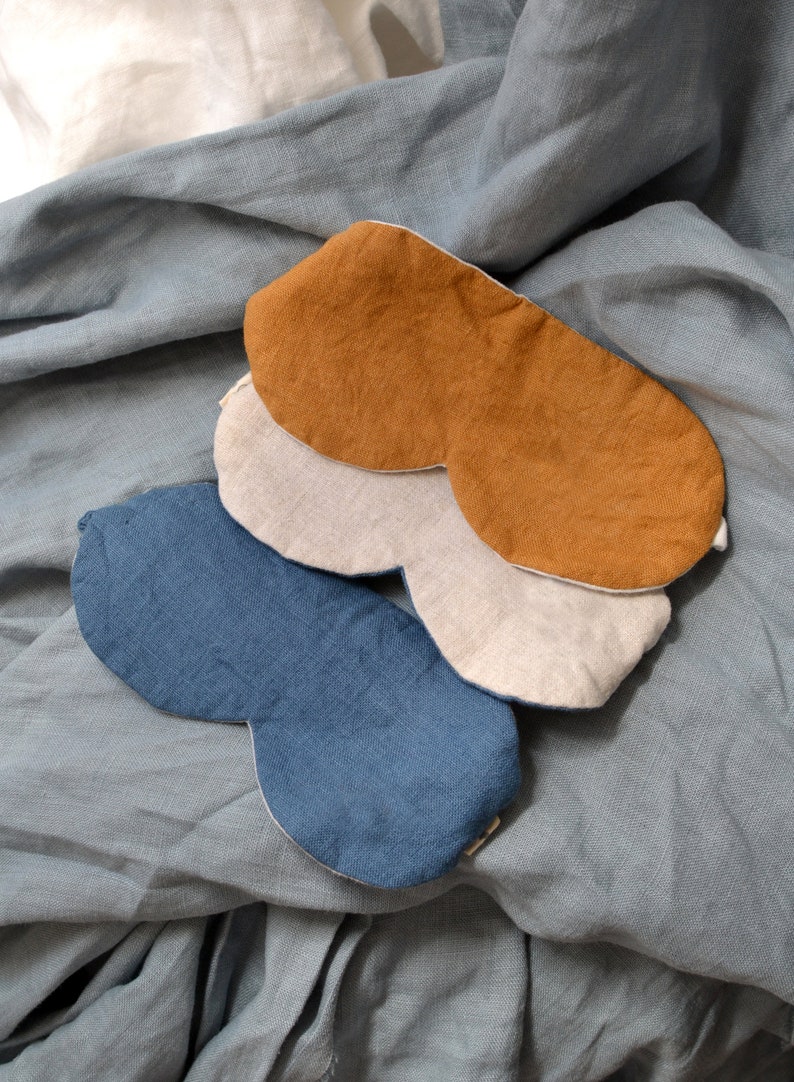 May include: Three sleep masks made of different fabrics. The top mask is a brown linen, the middle mask is a beige linen, and the bottom mask is a blue linen.