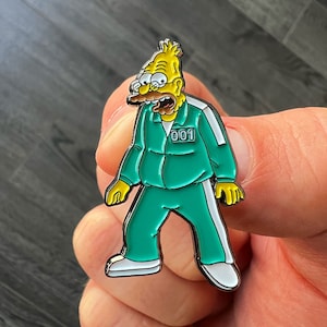 May include: A yellow cartoon character wearing a green jumpsuit with white stripes and a black number "001" on the chest. The character has a brown mustache and is holding a yellow object in each hand.