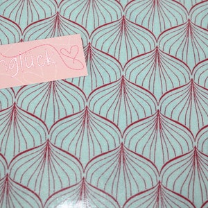 Puede incluir: Una tela azul claro con un patr&oacute;n repetitivo de formas de hojas granates. Una tarjeta rosa con la palabra "n&auml;hgl&uuml;ck" y un coraz&oacute;n est&aacute; colocada encima de la tela.