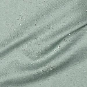 Könnte beinhalten: Nahaufnahme eines hellgrünen Stoffes mit subtiler Webstruktur. Wassertropfen sind über die Oberfläche verteilt, was auf ein wasserabweisendes Material hindeutet. Der Stoff ist leicht zerknittert.