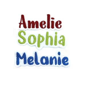 May include: Three embroidered name patches: "Amelie" in burgundy, "Sophia" in green, and "Melanie" in blue. Each name is in a cursive font with a white border, perfect for personalizing items.