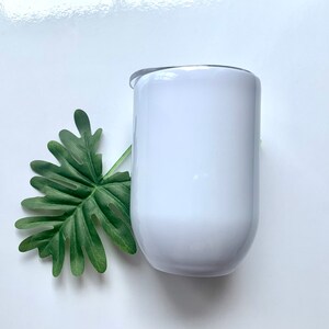 May include: White stainless steel tumbler with a lid. The tumbler is round and has a smooth surface.