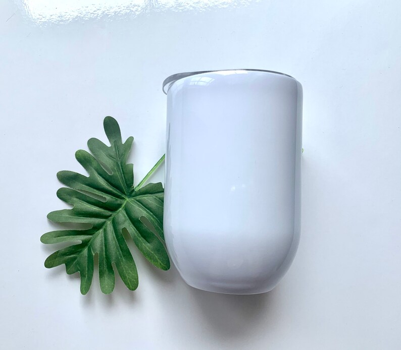 May include: White stainless steel tumbler with a lid. The tumbler is round and has a smooth surface.
