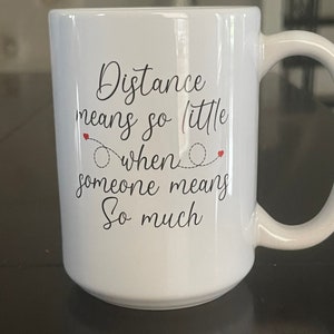 May include: White ceramic coffee mug with black text that reads "Distance means so little when someone means so much".