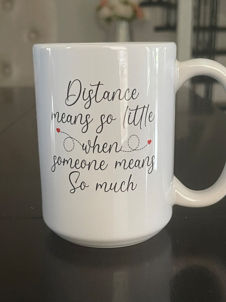 May include: White ceramic coffee mug with black text that reads "Distance means so little when someone means so much".
