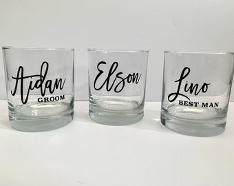 May include: Three clear glass tumblers with black lettering. The first tumbler says "Aidan Groom", the second tumbler says "Elson", and the third tumbler says "Lino Best Man".