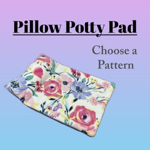 May include: A rectangular potty pad with an attached pillow, featuring a white fabric base with a floral pattern of pink, purple, and yellow flowers. The text Pillow Potty Pad and Choose a Pattern is printed above the pad on a gradient background.