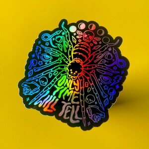 May include: A rainbow holographic sticker with a spider design and the text "Only time will tell".