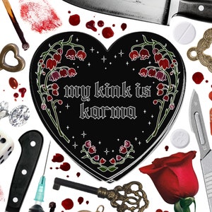May include: A black heart-shaped pin with the text "my kink is karma" surrounded by red and white flowers. The pin is surrounded by various objects including a key, a knife, a lighter, matches, a scalpel, a syringe, a rose, and blood drops.