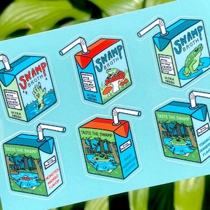 May include: Six colorful stickers featuring cartoon illustrations of juice boxes with the text "Swamp Broth" and various flavors. The stickers are on a light blue background.