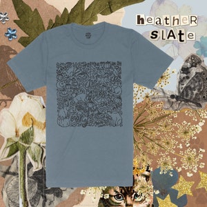 K&ouml;nnte beinhalten: Ein T-Shirt in der Farbe Schieferblau mit einem schwarzen und wei&szlig;en Halloween-Motiv. Das Motiv zeigt verschiedene Halloween-Symbole wie K&uuml;rbisse, Geister, Flederm&auml;use und Katzen. Der Text auf dem Motiv lautet "Spooky", "Boo", "Haunted" und "Oh No".