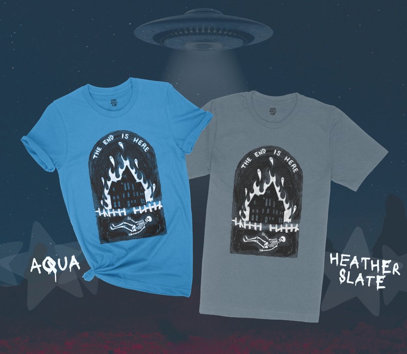 Op de afbeelding: Twee T-shirts met een grafische print van een brandend huis met een skelet dat ervoor ligt. De tekst "The end is here" is boven het huis gedrukt. De T-shirts zijn in de kleuren aqua en heather slate.