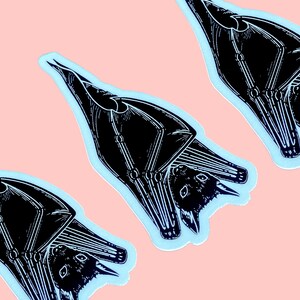 May include: Three black and white bat stickers on a light pink background. The bats are upside down with their wings spread out. The stickers are outlined in light blue.