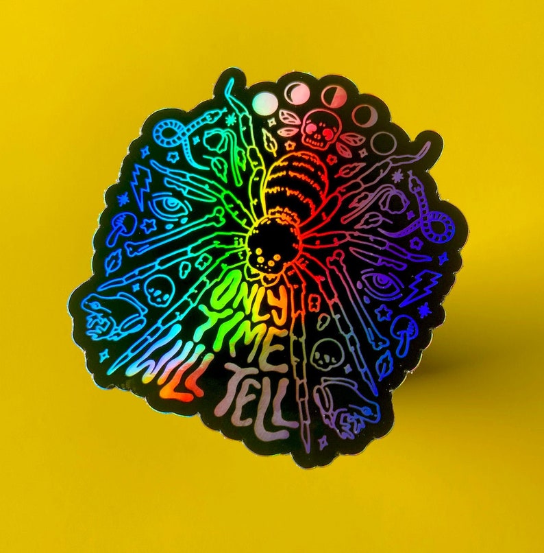 May include: A rainbow holographic sticker with a spider design and the text "Only time will tell".