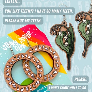 May include: A pair of wooden earrings with a circle design featuring a pattern of white teeth. The earrings are on a rainbow background with the text "Spiky Doodle Club" and "By Elaina Smith". The text "LISTEN.. YOU LIKE TEETH?? I HAVE SO MANY TEETH. PLEASE BUY MY TEETH." is at the top of the image. The text "PLEASE. I DON'T KNOW WHAT TO DO WITH ALL OF THESE TEETH." is at the bottom of the image.