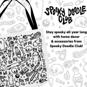 Op de afbeelding: Een witte tote bag met een zwarte handvat en een zwart-witte illustratie van griezelige krabbels. De krabbels omvatten een schedel, een kruis, een kist, een tand, een bom, een schop, een mes, een fles, een sleutel en de woorden "Oh No". De tekst "Spooky Doodle Club" staat in het zwart bovenaan de tas.