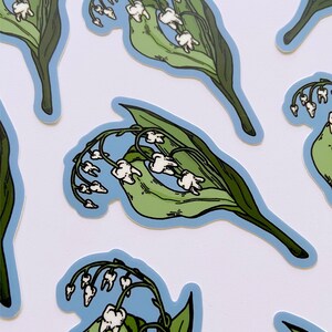 May include: A set of five stickers featuring a whimsical illustration of a lily of the valley flower with teeth. The flowers are white and the leaves are green. The stickers are printed on a blue background.