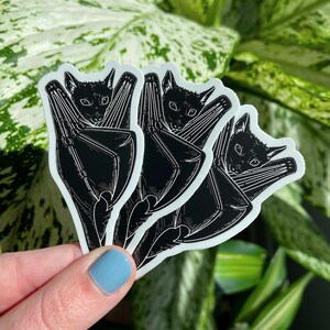 May include: Three black and white bat stickers with a simple line art design. The bats are depicted hanging upside down with their wings folded.
