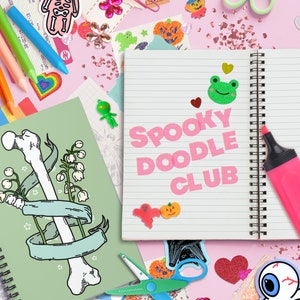 Op de afbeelding: Een roze notitieboek met de woorden "Spooky Doodle Club" in roze letters. Het notitieboek is omringd door verschillende stickers, waaronder een groene kikker, een spook, een vleermuis en een pompoen. Er zijn ook wat kleurpotloden, scharen en een roze markeerstift.