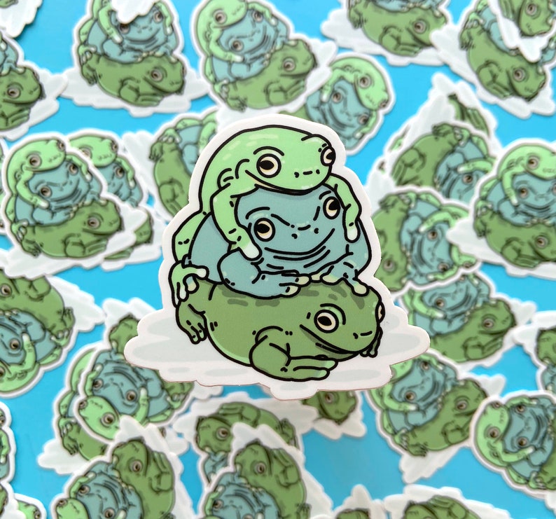 May include: A sticker featuring a stack of three green frogs. The bottom frog is the largest and the top frog is the smallest. The frogs are all facing forward with their mouths closed. The sticker is on a white background.