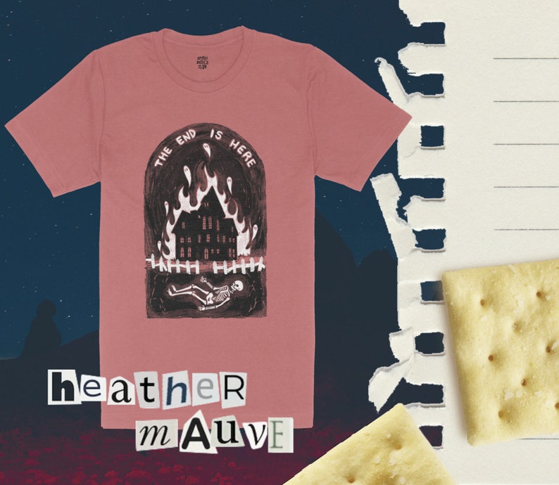 Op de afbeelding: Een roze T-shirt met een afbeelding van een brandend huis en een skelet. De tekst "The End Is Here" staat boven de afbeelding. De tekst "heather mAuve" staat onder de afbeelding.