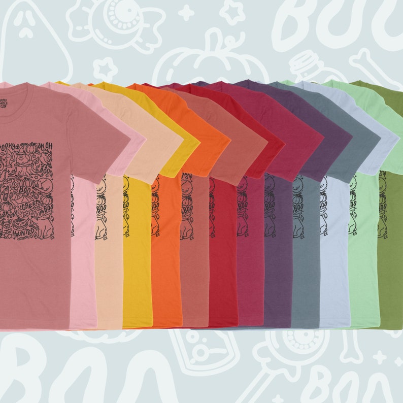 K&ouml;nnte beinhalten: Eine Reihe von 12 T-Shirts in verschiedenen Farben, mit einem schwarz-wei&szlig;en Grafikdruck eines Geistes, K&uuml;rbissen und dem Wort "Boo!" auf der Vorderseite. Die Shirts sind in einem Farbverlauf von Pink bis Gr&uuml;n angeordnet.