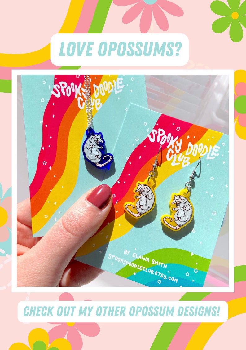 Pode incluir: Um colar e brincos com desenhos de gamb&aacute;. O colar tem um pingente de gamb&aacute; azul, e os brincos t&ecirc;m pingentes de gamb&aacute; amarelos. O texto "LOVE OPOSSUMS?" e "CHECK OUT MY OTHER OPOSSUM DESIGNS!" s&atilde;o vis&iacute;veis.