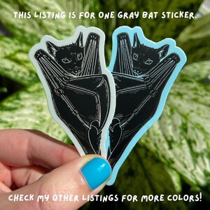 May include: Two gray bat stickers with a black silhouette of a bat with its wings folded around its body. The text "THIS LISTING IS FOR ONE GRAY BAT STICKER." is at the top of the image. The text "CHECK MY OTHER LISTINGS FOR MORE COLORS!" is at the bottom of the image.