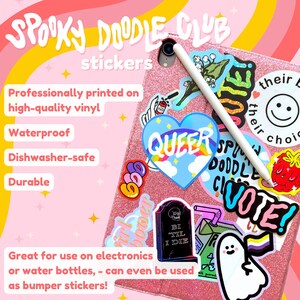 May include: A pink glitter phone case with various colorful stickers, including a heart with the word "QUEER" in rainbow letters, a ghost with a rainbow flag, a tombstone with the text "BI TIL I DIE", and a sticker that says "VOTE!"