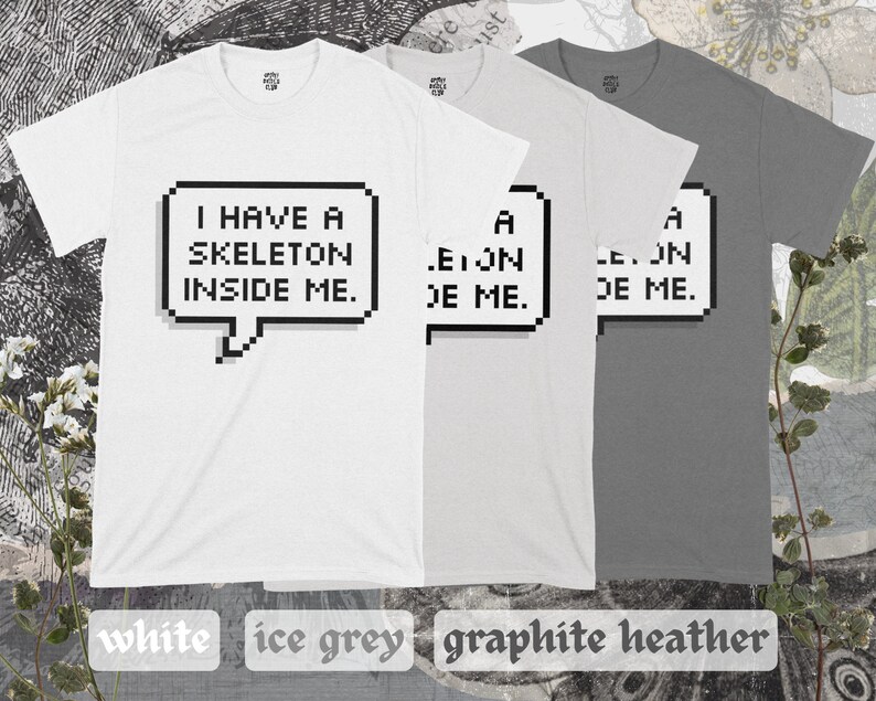 May include: Three t-shirts in white, light gray, and dark gray with a pixelated speech bubble graphic that says "I have a skeleton inside me."
