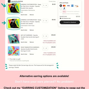 Op de afbeelding: Screenshot van een Etsy-winkelwagen van SpookyDoodleClub, met opties voor het aanpassen van oorbellen en andere items. De winkelwagen bevat items zoals Bat Cat Oorbellen en Dead Tamagotchi Oorbellen. Tekst op de afbeelding bevat "Alternatieve oorbelopties zijn beschikbaar!" en "Geen gaatjes in je oren? Geen probleem!"