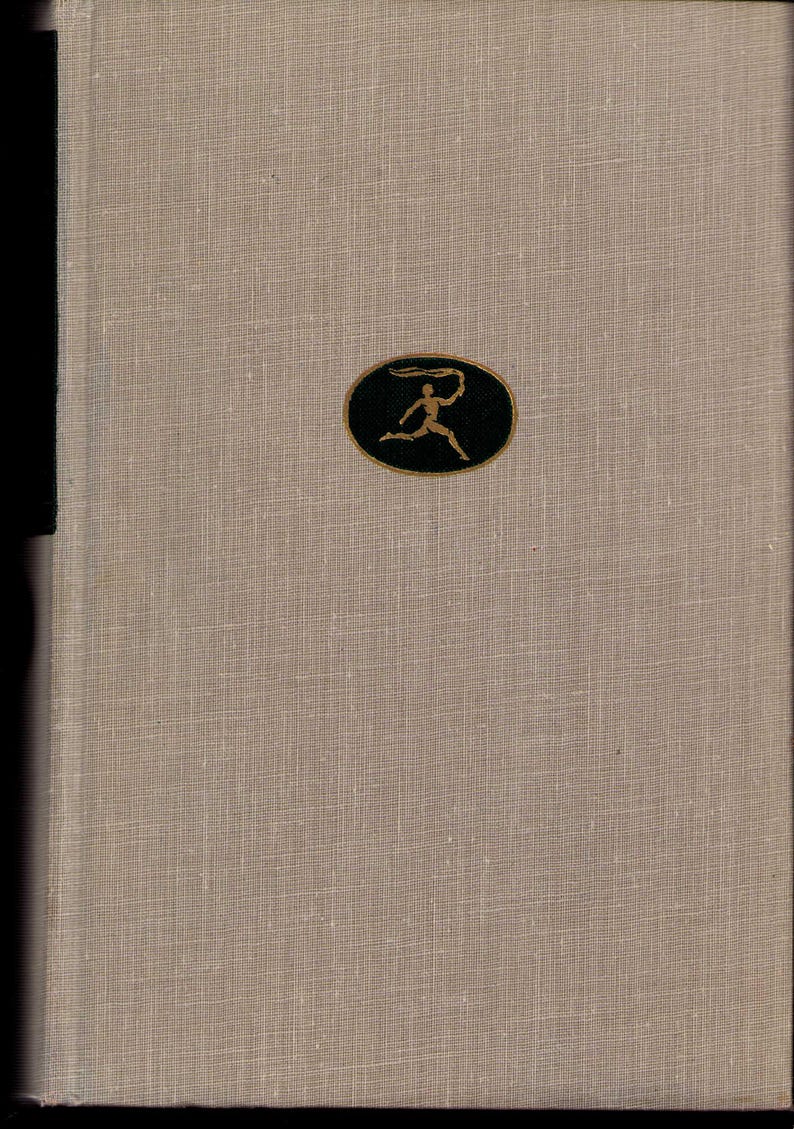May include: A hardcover book with a beige linen cover. A black oval emblem with a gold figure holding a flowing object is centered on the cover. The book's spine is a darker shade of beige.