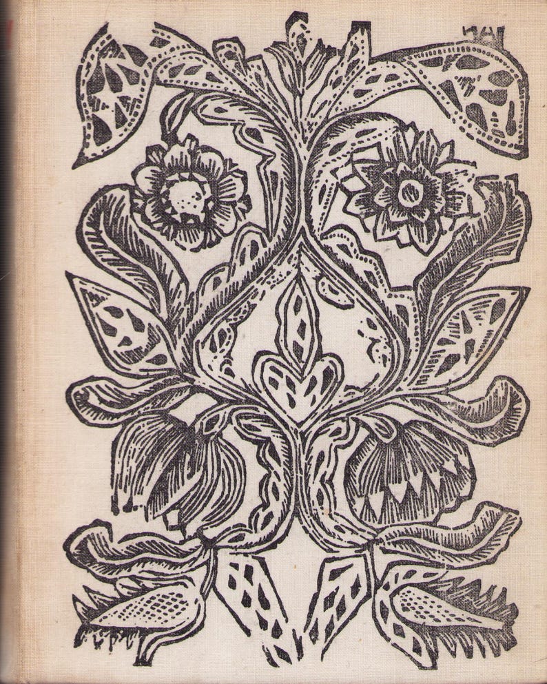 May include: Black and white floral woodcut print featuring stylized flowers, leaves, and decorative elements. The symmetrical design includes detailed linework, creating a vintage aesthetic. The print is on a cream-colored background.