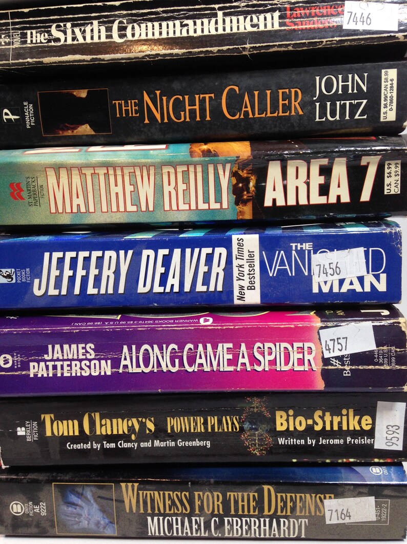 May include: A stack of paperback books with titles including "The Night Caller," "Area 7," and "Along Came a Spider." The spines display author names and book titles in various fonts and colors, with price stickers visible.