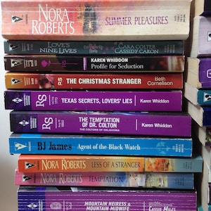 Może przedstawiać: Stos książek w miękkiej oprawie o tematyce romansu. Widoczne tytuły to "Summer Pleasures", "Love's Nine Lives" i "The Christmas Stranger". Książki ułożone pionowo, prezentują r&oacute;żnorodność autor&oacute;w i wzor&oacute;w okładek.