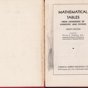 Op de afbeelding: Open boek met de titel "MATHEMATICAL TABLES" uit het "HANDBOOK OF CHEMISTRY AND PHYSICS". De omslag is gebroken wit met zwarte tekst. Het boek is een achtste editie, samengesteld door Charles D. Hodgman. Uitgegeven door CHEMICAL RUBBER PUBLISHING CO.