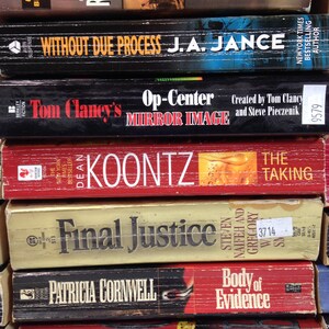 May include: A stack of paperback books with various titles and authors. Titles include "Sandstorm," "Without Due Process," "Op-Center Mirror Image," "The Taking," "Final Justice," "Body of Evidence," and "The Body Farm."
