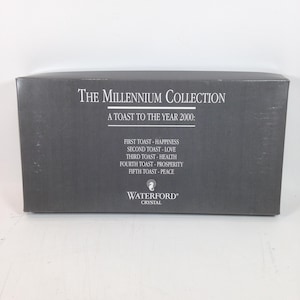 May include: A rectangular, dark gray box with the text "The Millennium Collection" and "A Toast to the Year 2000." The box lists toasts for happiness, love, health, prosperity, and peace. The Waterford Crystal logo is at the bottom.