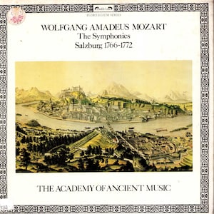 Puede incluir: Una portada de álbum vintage de "Las Sinfonías" de Wolfgang Amadeus Mozart, con una ilustración detallada del paisaje de Salzburgo de 1766-1772. La portada incluye el texto "The Academy of Ancient Music" y el logotipo de la serie Florilegium.