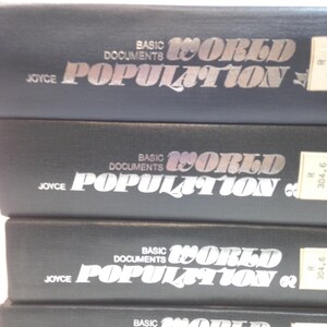 Könnte beinhalten: Ein Stapel schwarzer Bücher mit silberner Schrift. Die Bücher tragen den Titel "Basic Documents World Population" und sind mit "Joyce" beschriftet. Die Bücher haben Bibliotheksaufkleber an der Seite.
