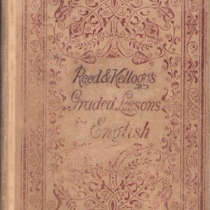 May include: Vintage book cover featuring the title "Reed & Kellogg's Graded Lessons in English." The cover is a light beige with a burgundy decorative border and floral pattern. A white sticker with numbers is in the lower left corner.