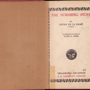 May include: Open book with the title "The Nürnberg Stove" by Louisa de la Ramé, illustrated by Maria L. Kirk. The cover is cream-colored with black decorative borders and text in red and black. The book is published by J. B. Lippincott Company.