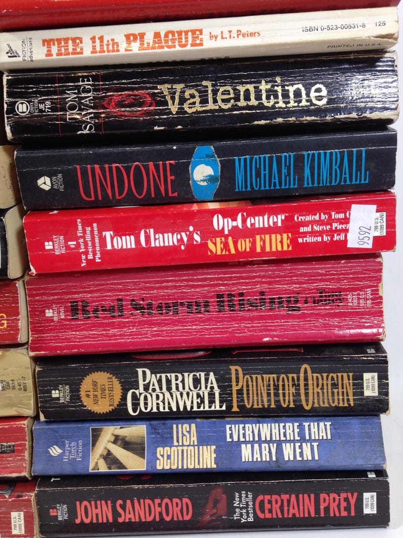 May include: A stack of paperback books with various titles and authors. The books have different colored spines, including red, black, and blue. Titles include "The 11th Plague," "Valentine," and "Undone."