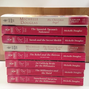Könnte beinhalten: Ein Stapel von zehn Liebesromanen von Michelle Douglas. Die Bücher sind alle rot mit goldenen Lettern und tragen Titel wie "Die Übernahme des spanischen Tycoons" und "Der Rebell und die Erbin".