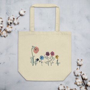 May include: A beige tote bag with a design of colorful flowers on a white background. The flowers are pink, purple, blue, yellow, and green.