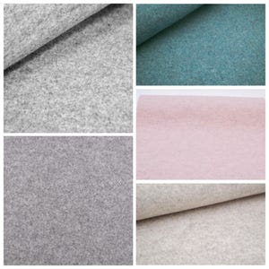 May include: A collection of five fabric swatches featuring a dense, felted texture. The colors include light gray, dark gray, teal, soft pink, and off-white. Each piece of fabric is shown folded or laid flat, highlighting the consistent, fuzzy surface.